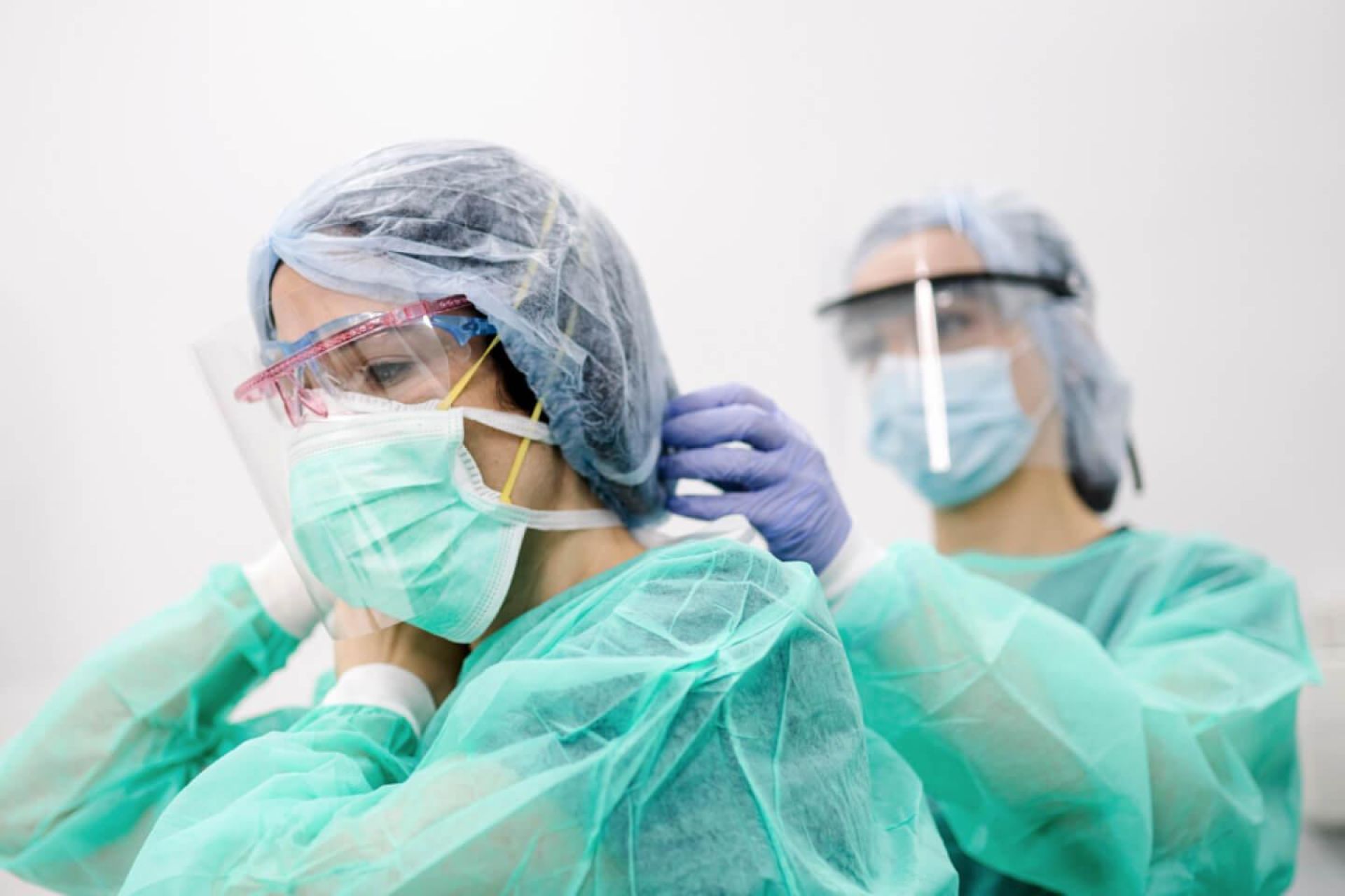 Two surgeons prepare ppe for each other