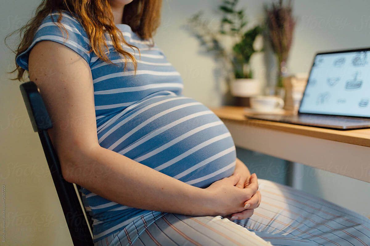 Pregnent women holding belly on a chair